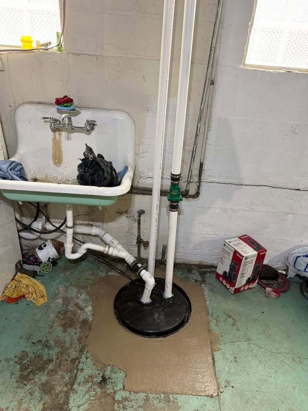 New sump pump basin and discharge piping installed on a basement floor