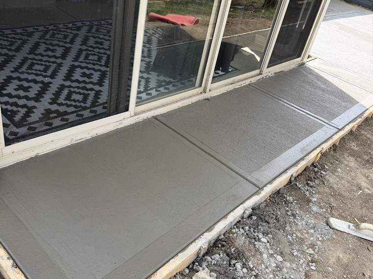 Freshly finished concrete pad poured outside a patio door