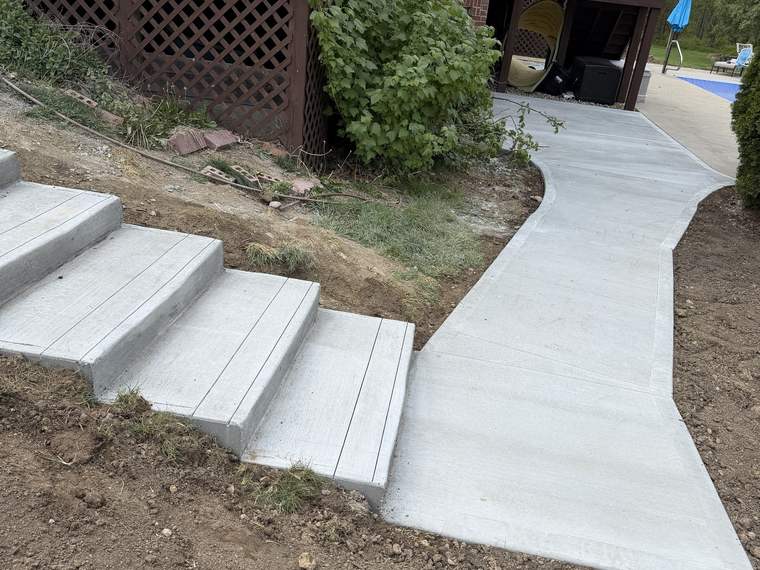 Finished concrete steps and curved walkway leading away from a house