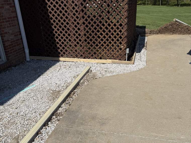 Concrete walk poured alongside a deck with a stone drainage edge