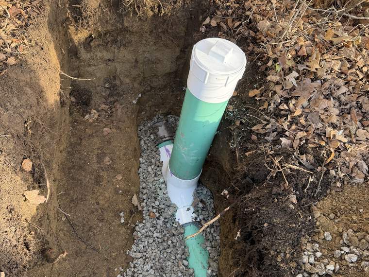 Drainage line outlet set in a gravel bed at the end of a trench