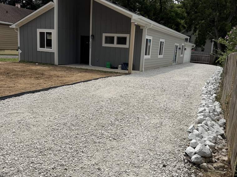 Finished gravel driveway running past a barn with a rip rap edge