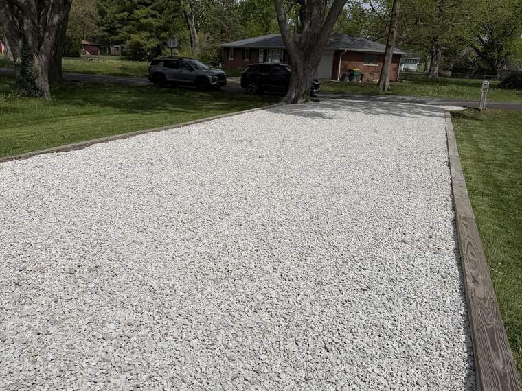 New crushed stone driveway installed between mature trees
