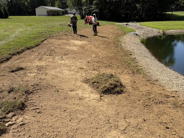 Crew walking a regraded pond bank after earthwork