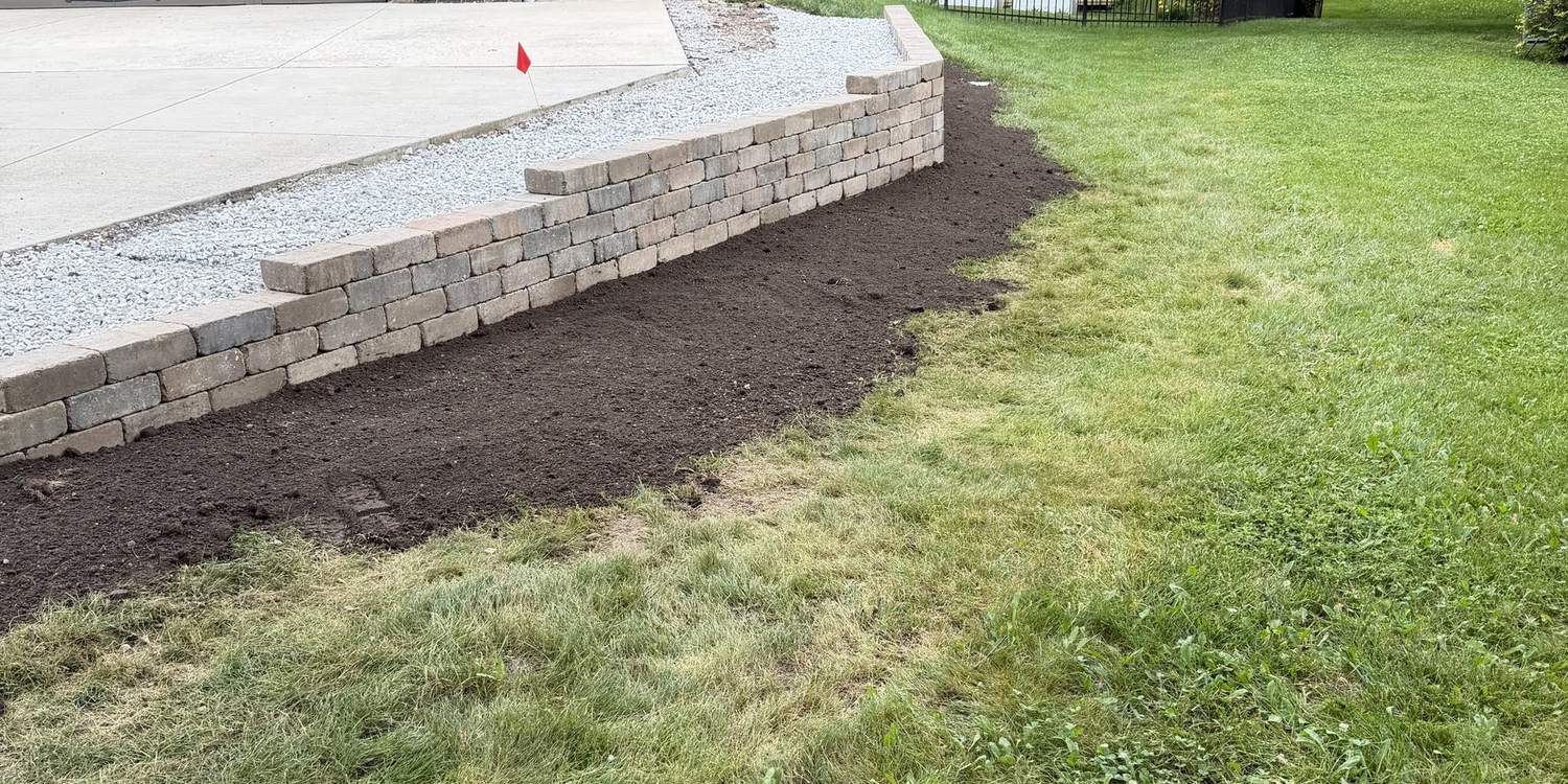 Finished block retaining wall with fresh mulch and restored lawn