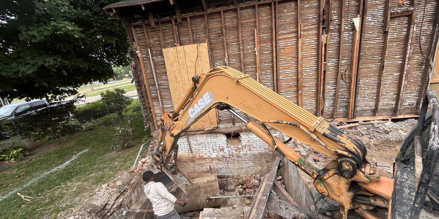 Excavator taking a structure down to its framing and foundation