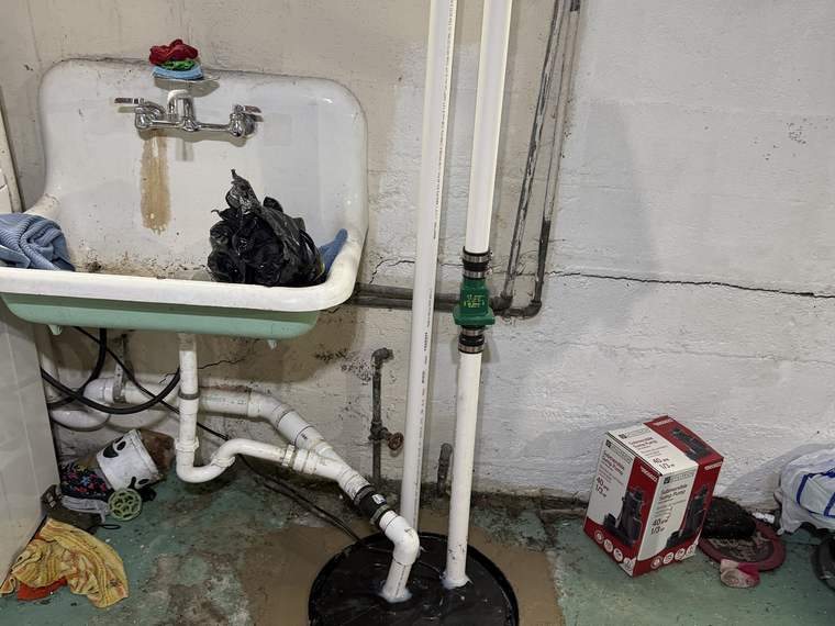 New sump pump and discharge piping installed on a basement floor