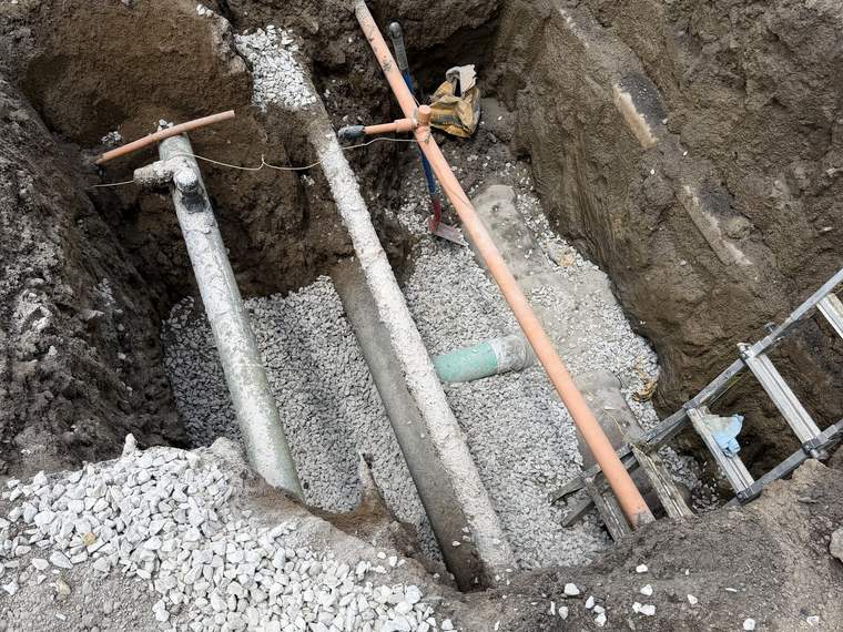 Deep utility trench with several service lines bedded in washed stone